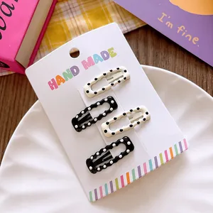 Close-up of four-piece polka dot BB hair clips on a handmade card display with stationery