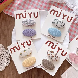 Detail of floral and solid fabric oval hair clips on display cards on a rustic background
