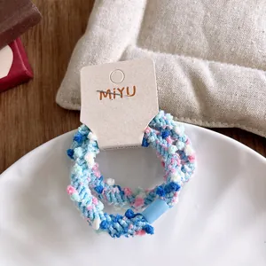 Détail d'élastiques à cheveux tressés bleus et roses sur une assiette en céramique