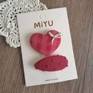 Dettaglio di fermagli per capelli in tessuto rosso e rosa con fiocco su legno