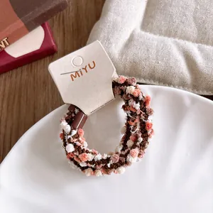 Détail d'un chouchou en peluche coloré avec perles tissées sur une assiette en porcelaine