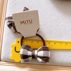 Détail d'un chouchou à nœud vichy marron de 4,5 cm avec élastique sur carton