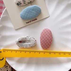 Floral and solid color oval fabric snap hair clips for girls on a white ceramic plate