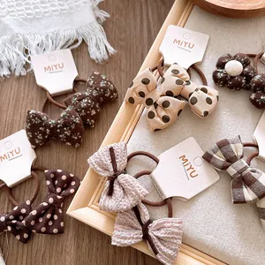 Détail de chouchous à nœuds en tissu avec motifs à pois et fleurs pour fillettes