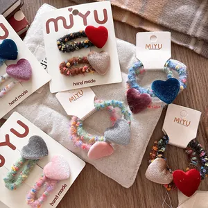Dettaglio di fermagli per capelli a cuore in velluto e lacci elastici intrecciati a mano