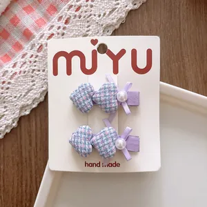 Détail de pinces à cheveux avec nœuds violets et cœurs à carreaux sur carton