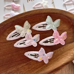 Détail de cinq pinces à cheveux papillon colorées avec des étoiles pailletées sur bois