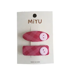 Fermagli per capelli in tessuto a scacchi rosa con bottone su carta bianca