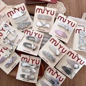 Detail view of silver bow and star hair clips set on a branded display card