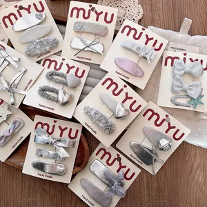 Detail of handmade silver bow hair clips with glitter hearts on packaging cards