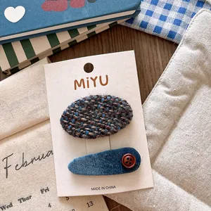 Detail of tweed and corduroy hair clips with a vintage button on a display card