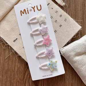 Détail de cinq barrettes à paillettes en forme d'étoile pour filles sur support