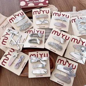 Detailed close-up of handmade silver bow hair clips on premium card packaging