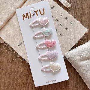 Détail de cinq pinces à cheveux en forme de cœur pailleté pour filles tons pastel