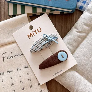 Detail of blue bow and houndstooth fabric hair clips for girls on display card