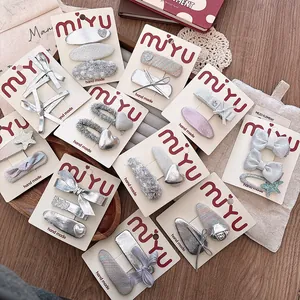 Close-up of silver leather bow hair clips and tweed hairpins on a gift display card