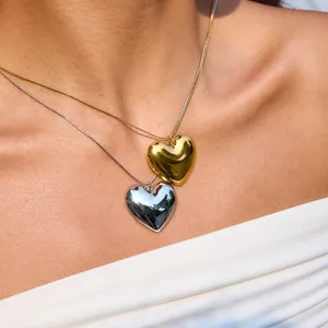 Détail rapproché de colliers avec pendentif cœur poli en or 18 carats et argent sur peau