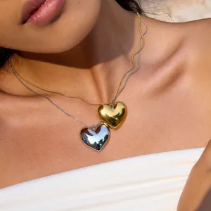 Collier pendentif cœur en acier inoxydable poli sur mannequin, finition or et argent.