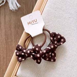 Détail des élastiques à cheveux à pois marron avec nœud sur carte de support