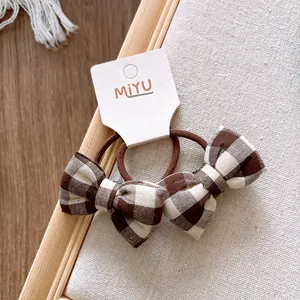 Détail de deux chouchous à nœuds en coton à carreaux sur carte de marque MIYU
