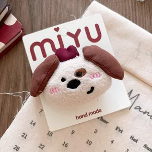 Detail of plush cartoon puppy hair clip with red heart and embroidery on display card
