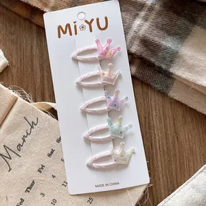 Détail de cinq barrettes à paillettes en forme de couronne pour filles sur carte papier
