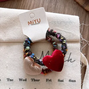 Dettaglio di elastici per capelli a cuore in velluto su confezione in cartoncino