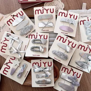 Silver bow and heart-shaped hair clip set for girls on elegant wooden tray