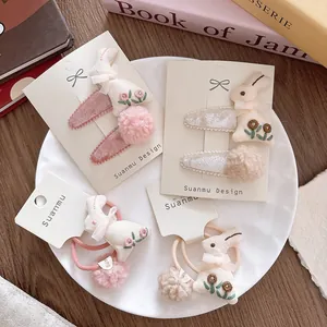 Detailed view of children's velvet bunny hair clips and ties with embroidery and pom-poms