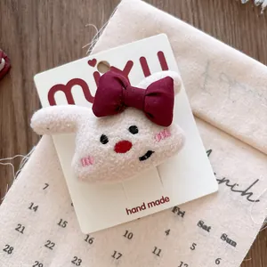 Close-up of handmade plush rabbit hair clip with red bow on rustic wooden background