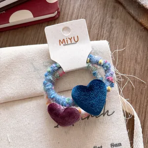 Dettaglio di elastici per capelli a cuore in velluto con corde in maglia su borsa