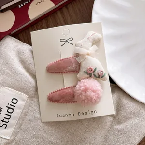 Detailed view of pink velvet hair clips with embroidered bunny and soft pompom decor