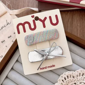 Detail of 2-piece hair clip set with rainbow fabric and silver bow on display card