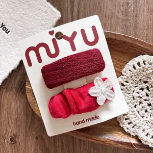 Detail of red knitted rectangular hair clip and velvet lace flower clip set on card