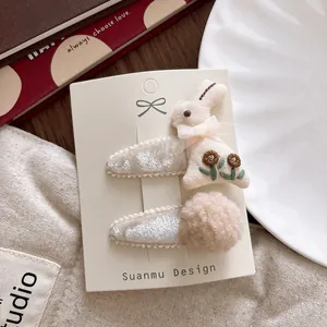 Detail of sweet embroidered rabbit and soft plush ball hair clips for little girls