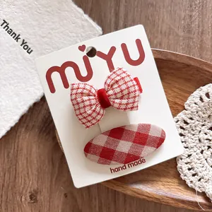 Detail of red and white plaid bow hair clips set on a decorative wooden background