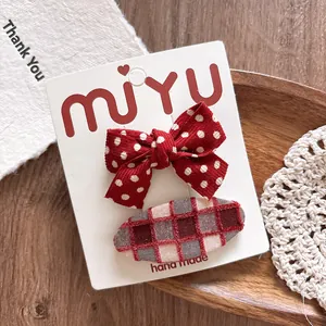 Macro shot of a 2-piece red bow hair clip set with polka dots and plaid fabric textures