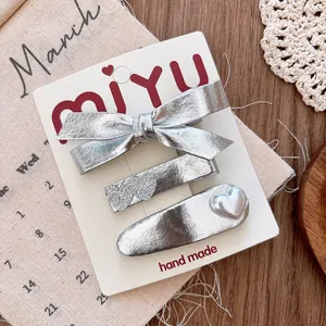 Detailed view of silver bow hair clips with heart sequins and pearls on a display card