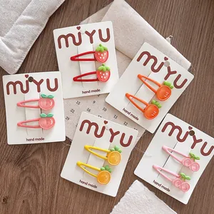 Kleurrijke aardbei en perzik haarspeldjes gepresenteerd op een witte kartonnen kaart