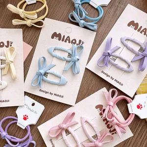 Barrettes et élastiques à cheveux nœuds en tissu aux tons pastel sur fond de bois