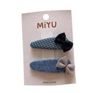 Set of two blue fabric bow BB clips with heart plaid patterns on a white display card