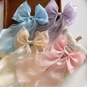 Macro shot of oversized organza bow hair clips in blue, purple, champagne and pink colors