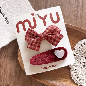 Detail of red checkered bow and velvet heart hair clips for girls set on lace