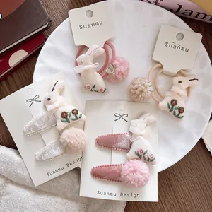 Detail of embroidered rabbit hair clips and plush pom-pom ties on a display card