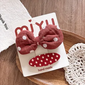 Detailed shot of handmade red polka dot bow and oval fabric hair clips set on card