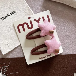 Detailed view of handmade pink star hair clips with brown leather tags on card
