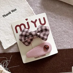 Detail view of handmade pink plaid bow hair clips and button clip on display card