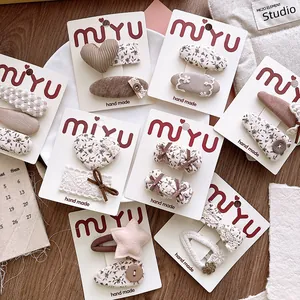 Close-up of assorted floral fabric hair clips in cream and brown on wooden background