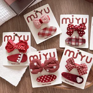 Close-up of red fabric bow hair clips with polka dots and plaid patterns on card