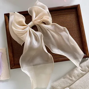 Macro view of a large champagne organza bow hair clip with translucent layered fabric